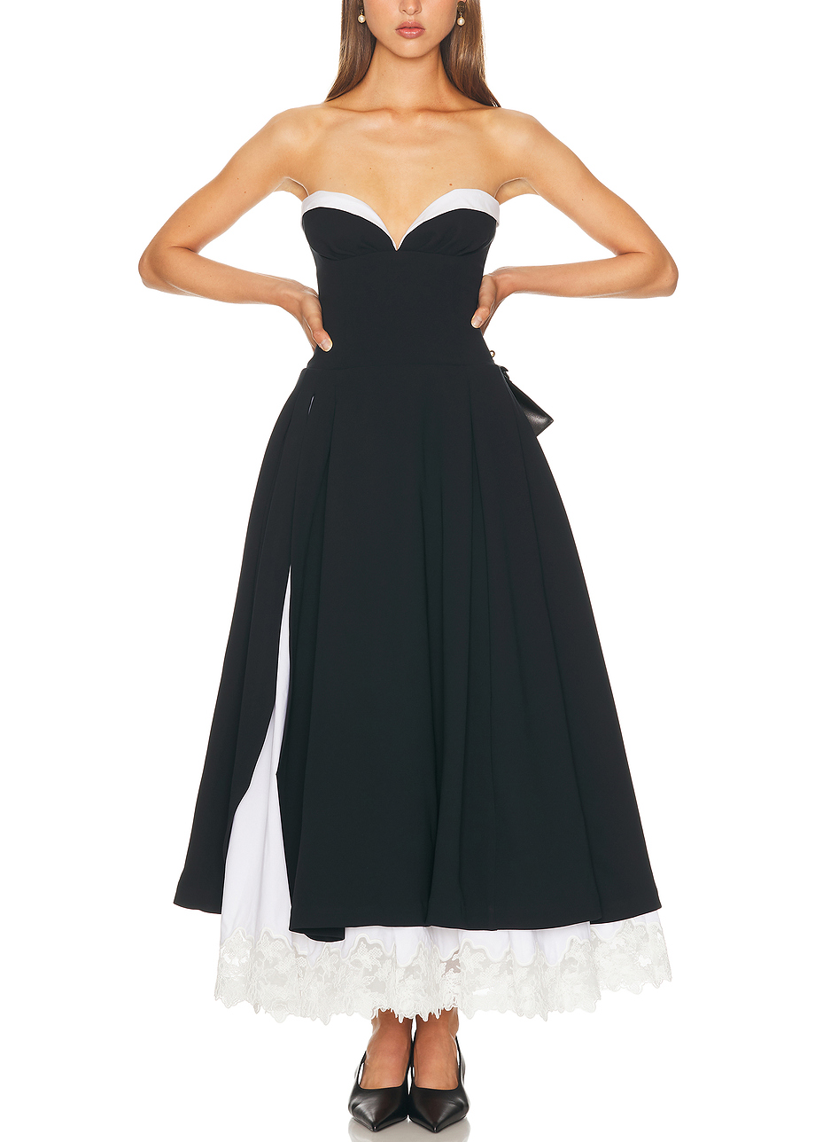 Woman wearing a black and white strapless dress with ruffled hem on a white background