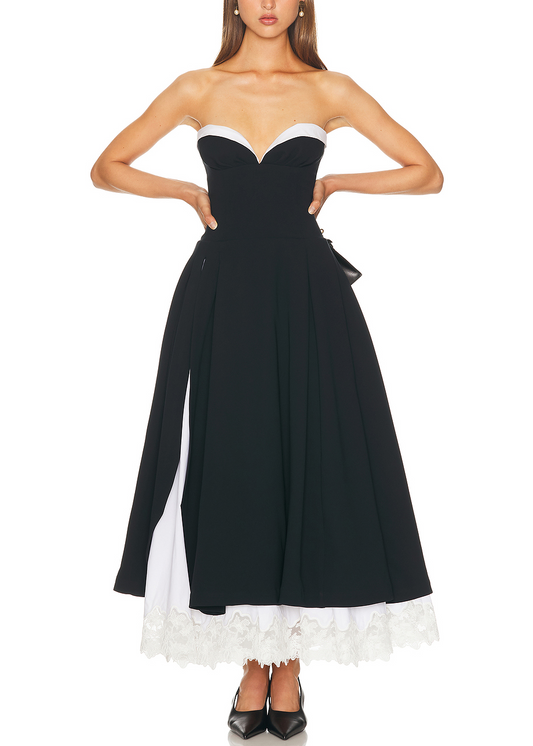 Woman wearing a black and white strapless dress with ruffled hem on a white background